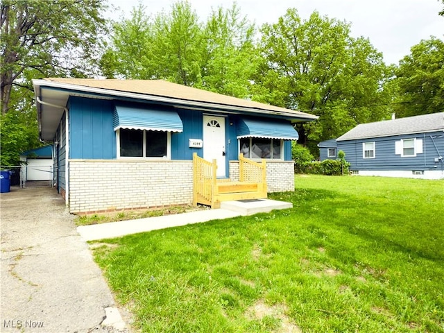 view of front of home with brick siding, a front lawn, an outbuilding, and board and batten siding