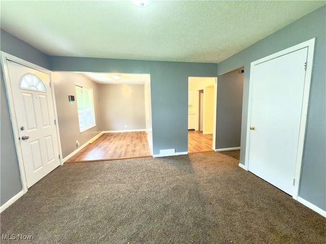 carpeted entryway with baseboards and a textured ceiling