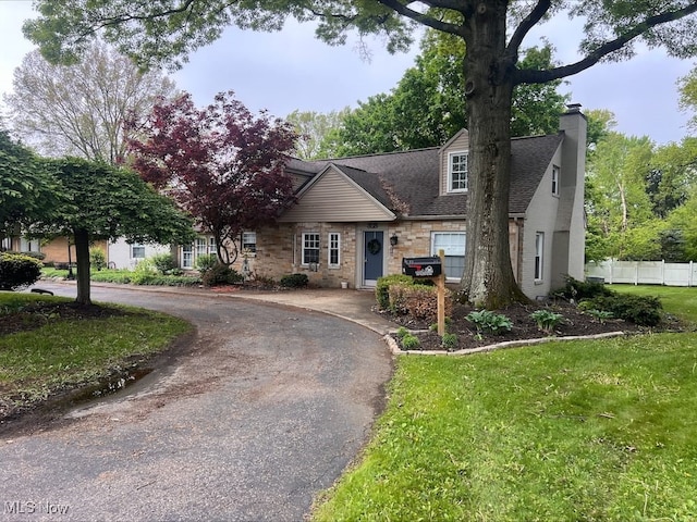 3118 Fulton Dr NW, Canton, OH 44718 - view of front of house featuring a chimney, stone siding, curved driveway, and roof with shingles