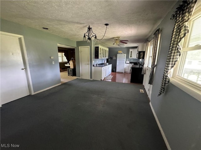 61272 Salem Rd, Salesville, OH 43778 - unfurnished living room with a textured ceiling, ceiling fan, baseboards, and dark carpet