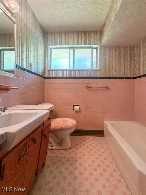 1010 Park Cir, Girard, OH 44420 - bathroom featuring tile patterned floors, tile walls, wallpapered walls, toilet, and a textured ceiling