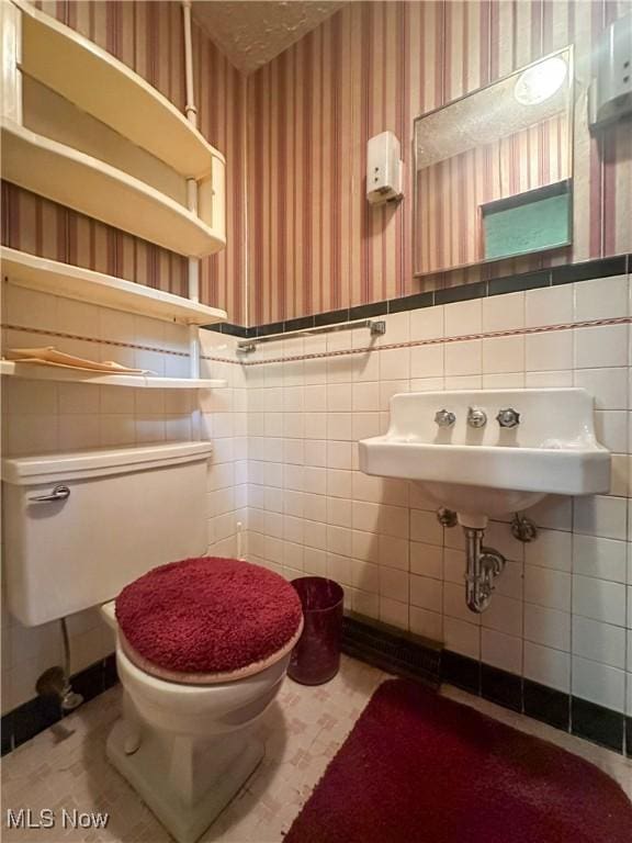 1010 Park Cir, Girard, OH 44420 - bathroom featuring wallpapered walls, a wainscoted wall, toilet, tile walls, and a sink