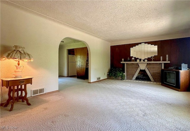 1010 Park Cir, Girard, OH 44420 - unfurnished living room featuring a textured ceiling, carpet, arched walkways, and a fireplace