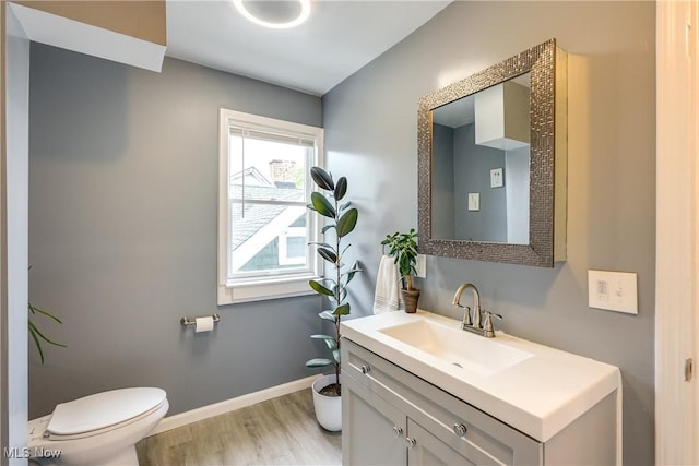bathroom featuring toilet, wood finished floors, vanity, and baseboards
