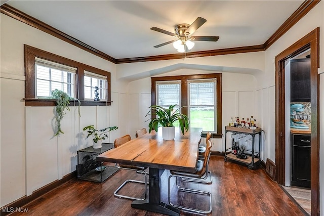 dining area with a decorative wall, crown molding, a ceiling fan, dark wood-style floors, and healthy amount of natural light