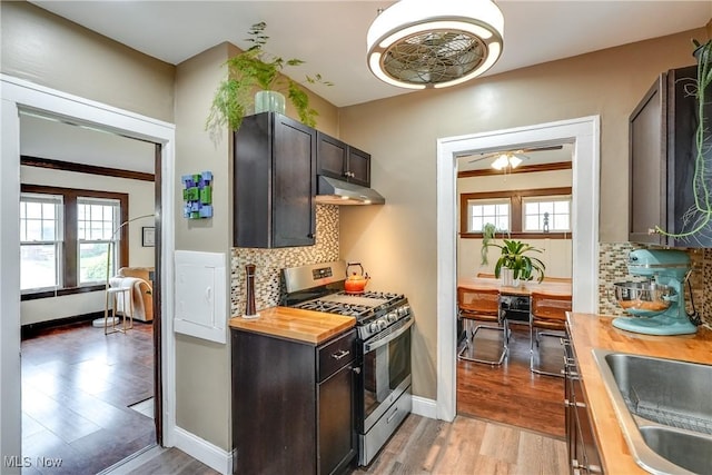 kitchen with gas stove, butcher block counters, under cabinet range hood, and light wood-type flooring