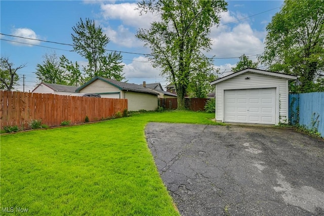 view of yard with an outbuilding, a garage, and asphalt driveway