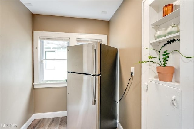 kitchen with freestanding refrigerator, open shelves, wood finished floors, and baseboards