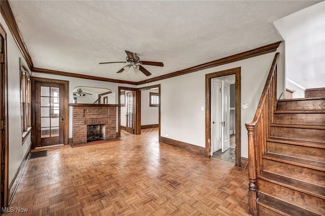 955 Dresden Rd, Cleveland Heights, OH 44112 - unfurnished living room featuring baseboards, a textured ceiling, ceiling fan, a brick fireplace, and stairway