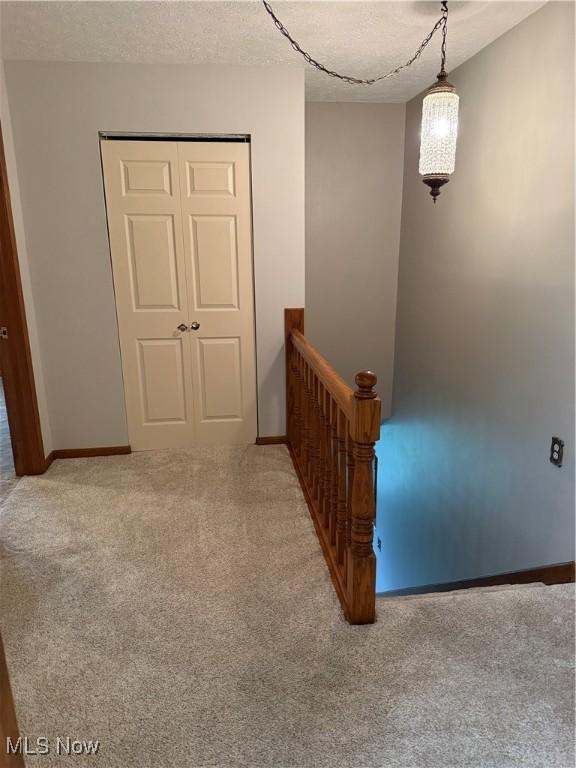 stairway with carpet, a textured ceiling, and baseboards