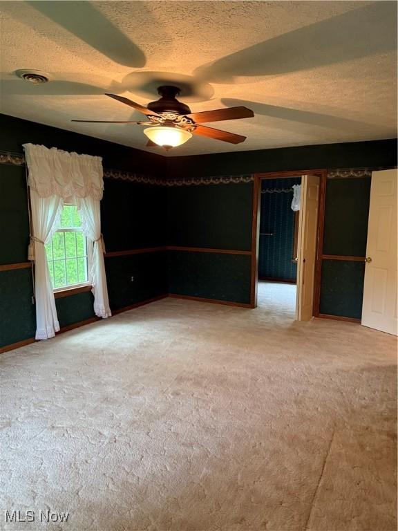 empty room with a ceiling fan, carpet flooring, and a textured ceiling