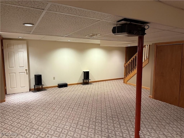 finished basement with carpet, a paneled ceiling, baseboards, and stairway