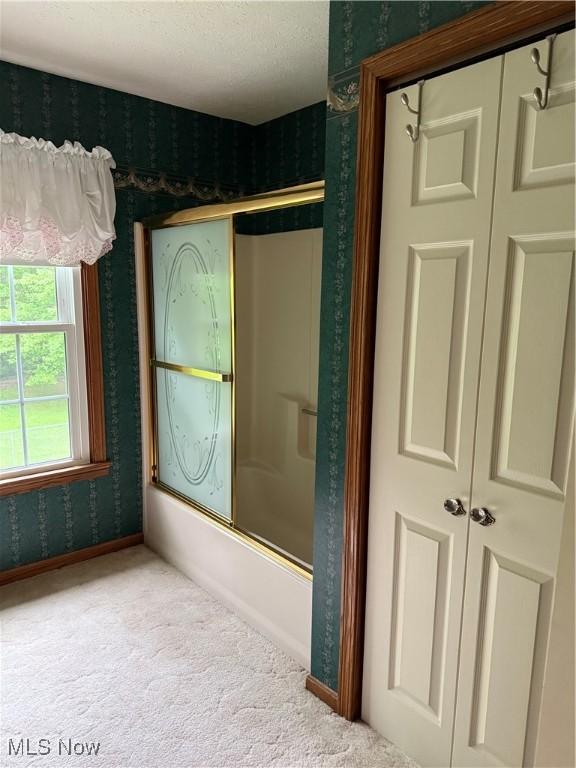 full bath featuring wallpapered walls, enclosed tub / shower combo, and baseboards
