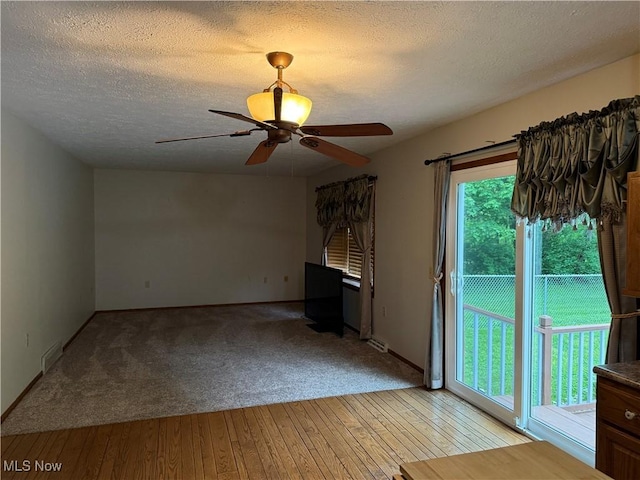 unfurnished living room featuring a textured ceiling, a ceiling fan, light wood-style floors, and light carpet