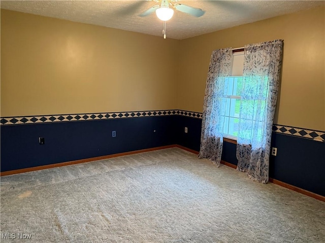 carpeted spare room featuring ceiling fan, a textured ceiling, and baseboards