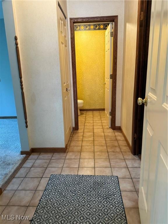 corridor featuring light tile patterned floors and baseboards