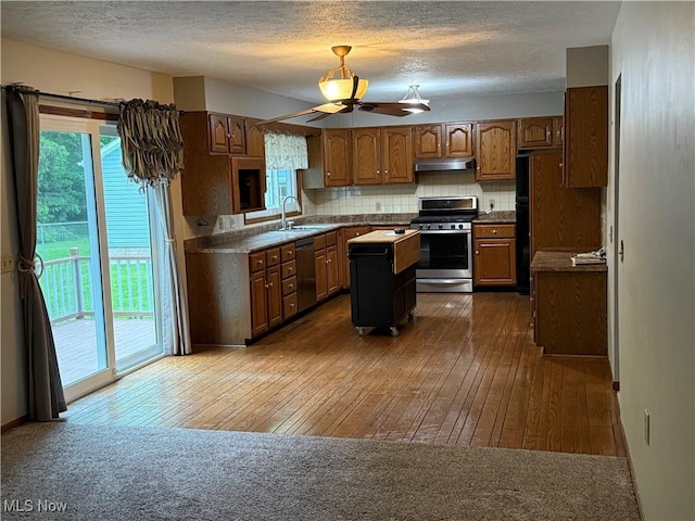 kitchen featuring appliances with stainless steel finishes, a sink, a kitchen island, dark wood finished floors, and a ceiling fan
