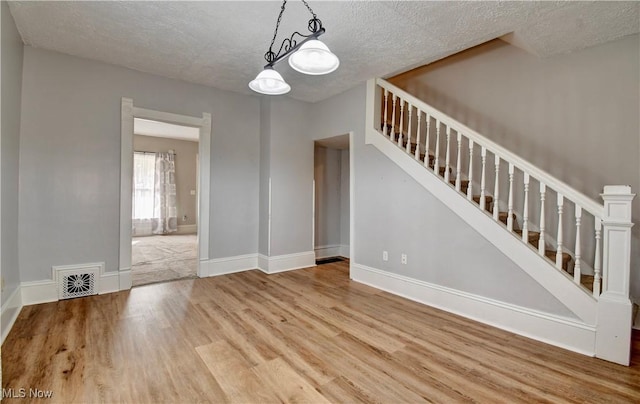 601 Short St, Dover, OH 44622 - empty room with wood finished floors, stairs, a textured ceiling, and baseboards