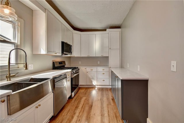601 Short St, Dover, OH 44622 - kitchen featuring appliances with stainless steel finishes, a sink, light wood-style floors, light countertops, and white cabinetry