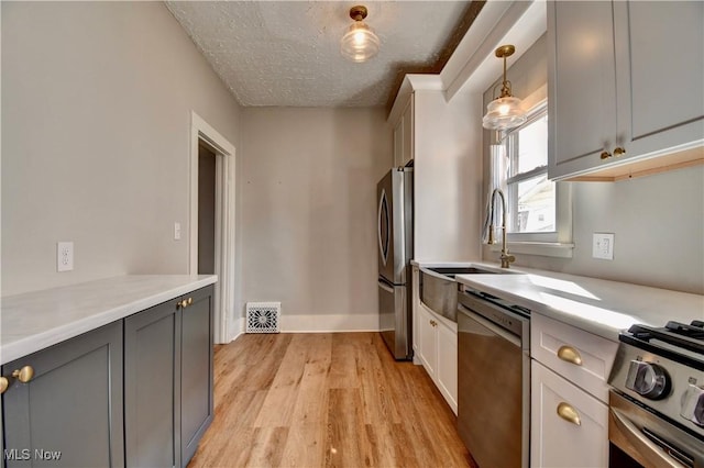 601 Short St, Dover, OH 44622 - kitchen featuring appliances with stainless steel finishes, light wood-style flooring, light countertops, a textured ceiling, and a sink