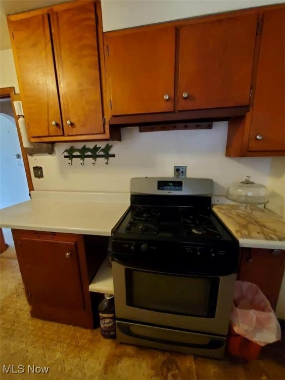 7417 Broadview Rd, Seven Hills, OH 44131 - kitchen with stainless steel gas range oven, light countertops, under cabinet range hood, and brown cabinets