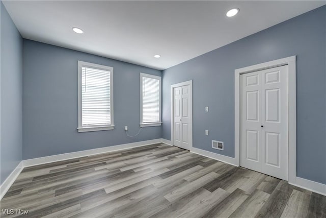 unfurnished bedroom with wood finished floors, baseboards, and recessed lighting