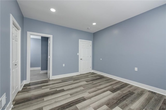 unfurnished bedroom featuring wood finished floors, baseboards, a closet, and recessed lighting