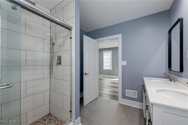 full bathroom with baseboards, a shower stall, double vanity, and tile patterned floors