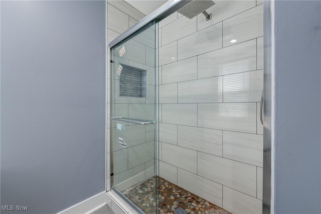 full bathroom with a stall shower and baseboards