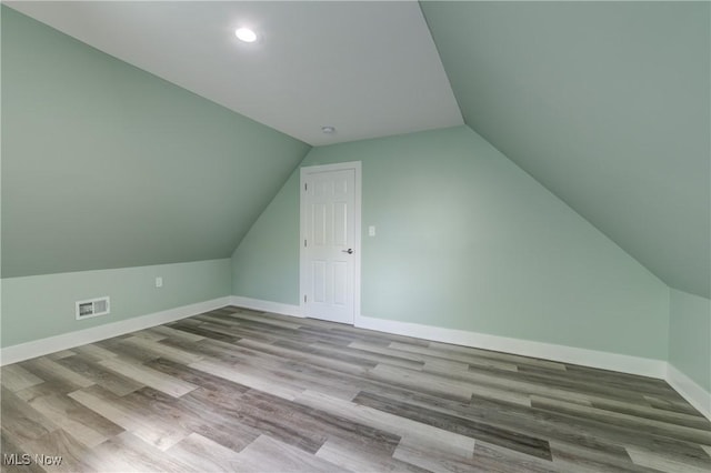 additional living space with vaulted ceiling, wood finished floors, baseboards, and recessed lighting