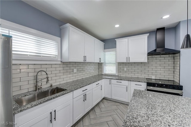 kitchen featuring wall chimney range hood, a sink, white cabinets, range with electric stovetop, and recessed lighting