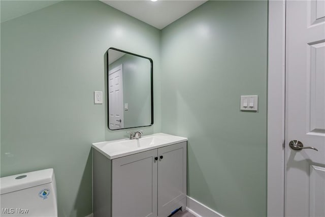 bathroom featuring baseboards, vanity, and toilet