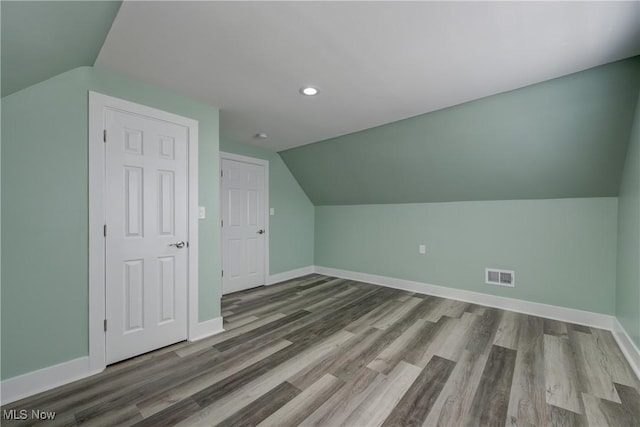 additional living space with lofted ceiling, baseboards, recessed lighting, and wood finished floors