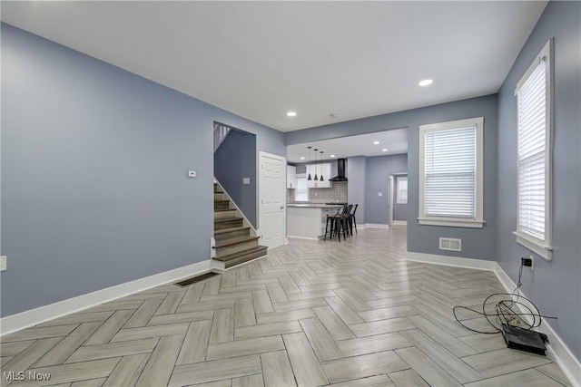 unfurnished living room with baseboards, stairs, and recessed lighting