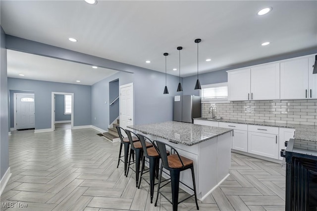 kitchen with freestanding refrigerator, baseboards, a sink, a kitchen island, and recessed lighting