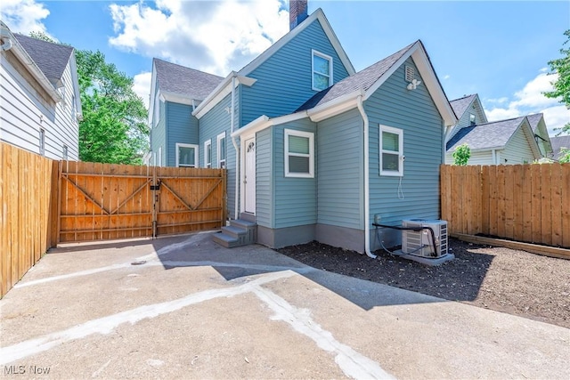 rear view of property featuring entry steps, fence, a gate, and central air condition unit