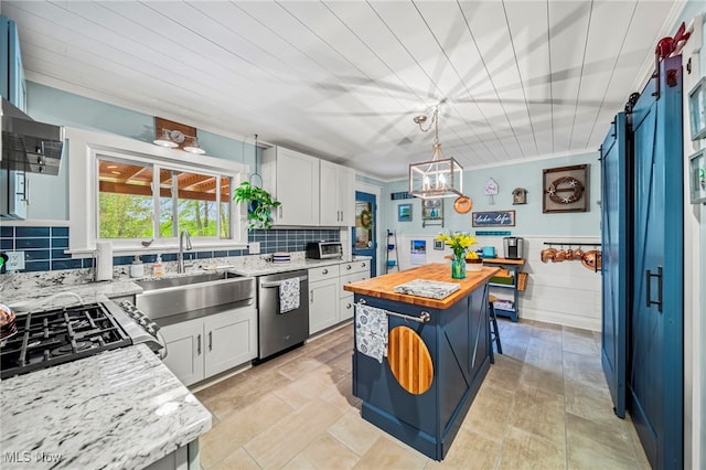 kitchen with appliances with stainless steel finishes, wooden counters, white cabinets, a sink, and tasteful backsplash