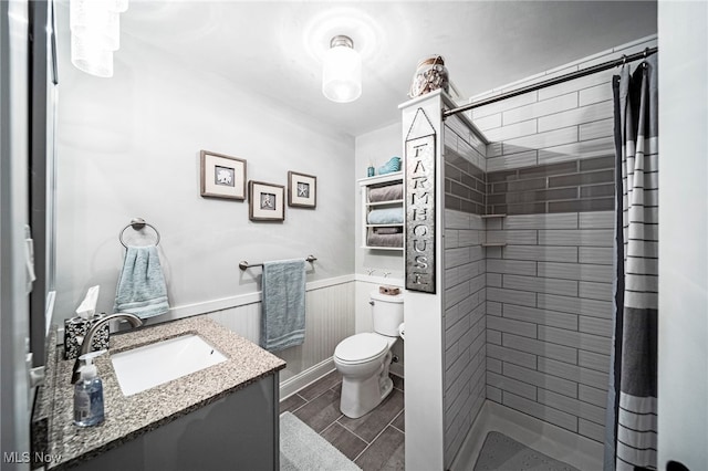 full bathroom with a tile shower, toilet, a wainscoted wall, vanity, and wood finish floors