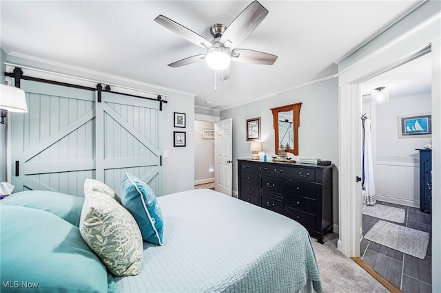 bedroom with a barn door, ornamental molding, ceiling fan, and baseboards