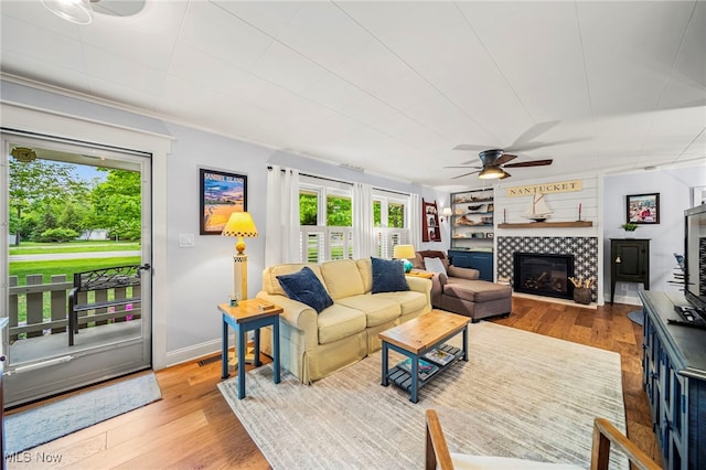 living room with ceiling fan, wood finished floors, a fireplace, and baseboards