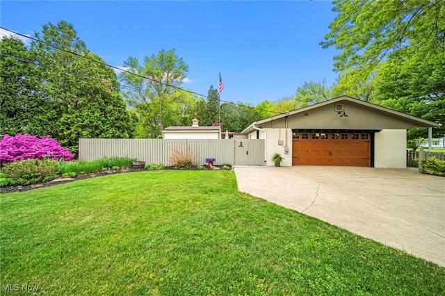 view of yard featuring concrete driveway, a gate, and a garage