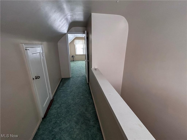 hall with carpet, vaulted ceiling, baseboards, and an upstairs landing
