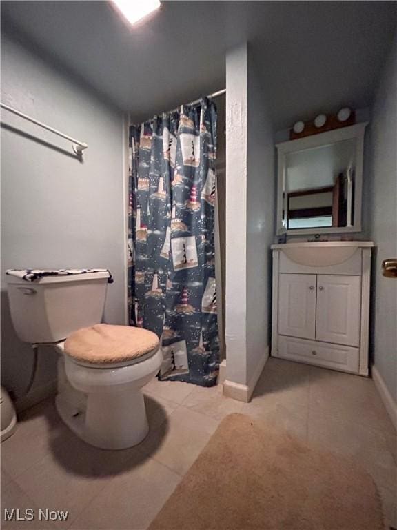 bathroom featuring toilet, a shower with shower curtain, vanity, tile patterned flooring, and baseboards