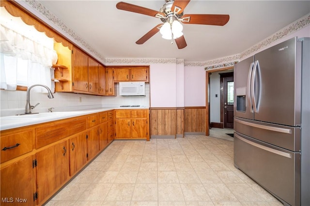 390 E Clark St, East Palestine, OH 44413 - kitchen featuring white appliances, a sink, brown cabinets, light countertops, and a wainscoted wall