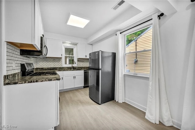 1212 Eastwood Ave, Mayfield Heights, OH 44124 - kitchen featuring appliances with stainless steel finishes, light wood-style floors, white cabinets, decorative backsplash, and baseboards