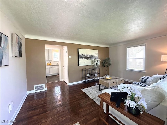 19708 Sunset Dr, Warrensville Heights, OH 44122 - living room featuring a textured ceiling, dark wood finished floors, and baseboards