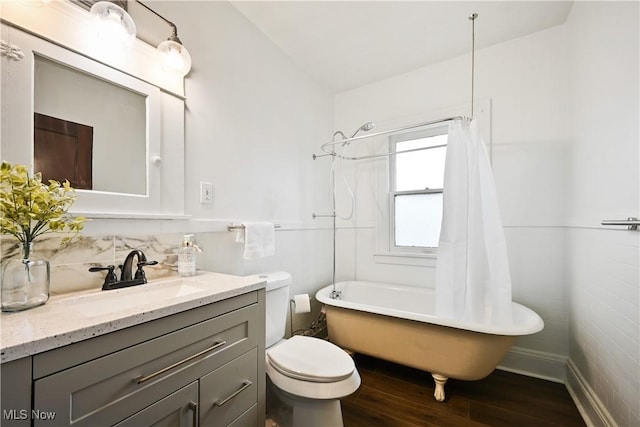 bathroom featuring wood finished floors, toilet, vanity, baseboards, and shower / bath combination with curtain