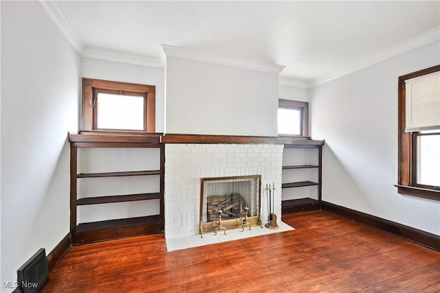 unfurnished living room featuring wood finished floors, baseboards, ornamental molding, and a brick fireplace