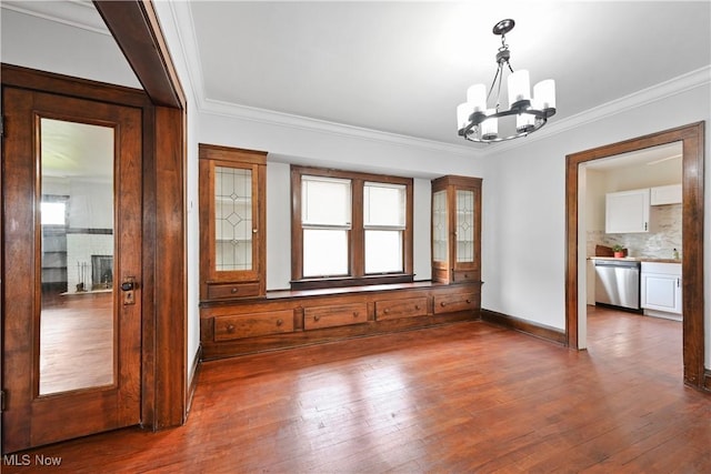 unfurnished room with a chandelier, dark wood-style flooring, ornamental molding, and baseboards