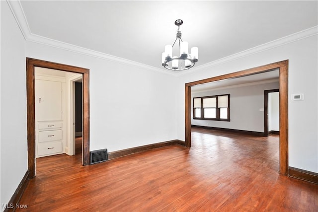 unfurnished room with a chandelier, baseboards, crown molding, and wood finished floors